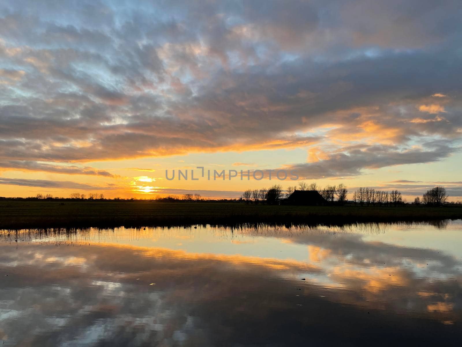 Winter sunset with clouds reflection in a lake around Sneek in Friesland The Netherlands