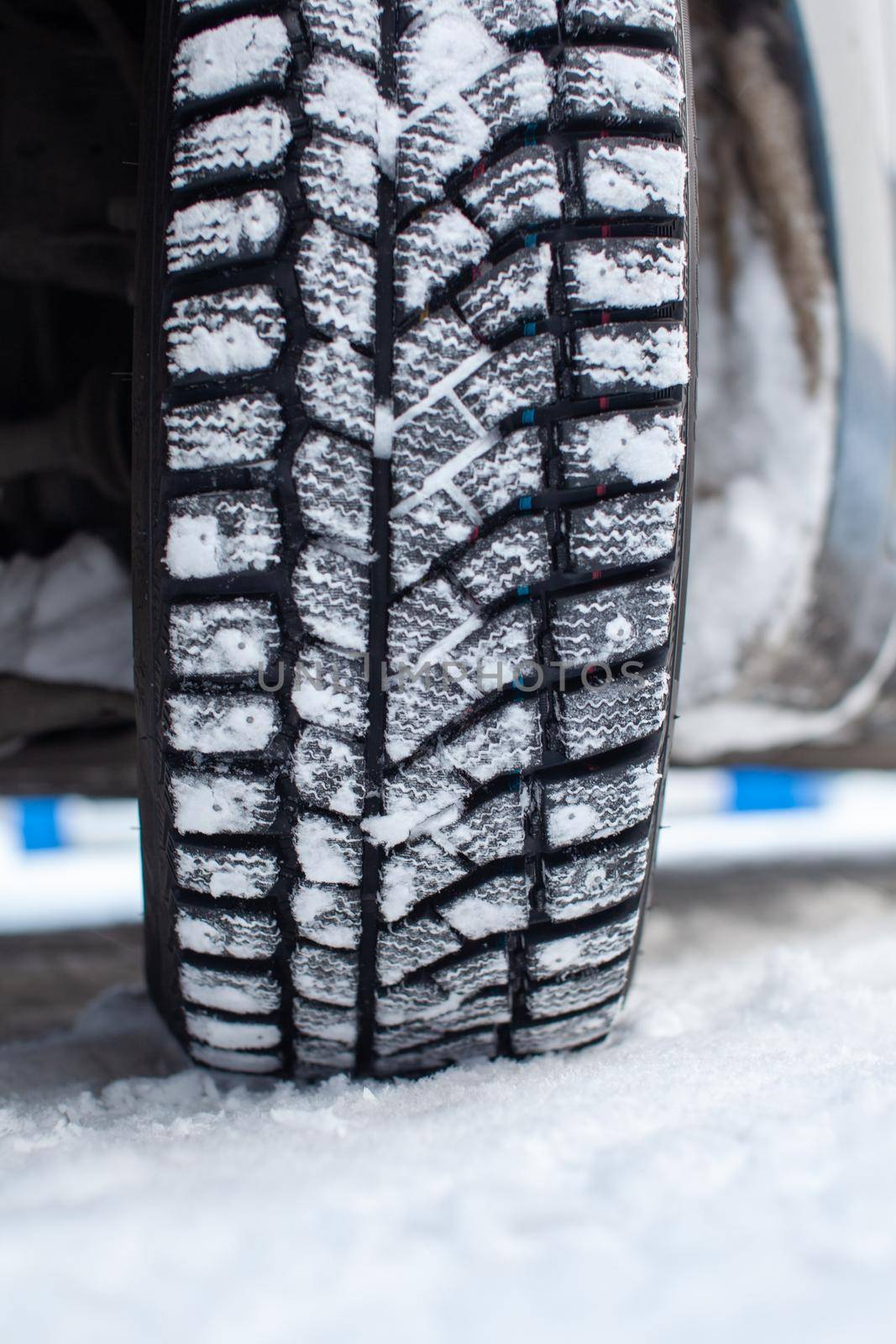Car tires on the winter road are covered with snow. A car on a snow-covered alley. A car wheel in the snow.