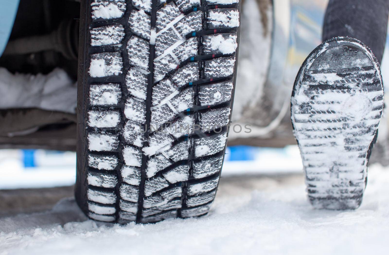 Car tires on the winter road are covered with snow. A car on a snow-covered alley. A car wheel in the snow.