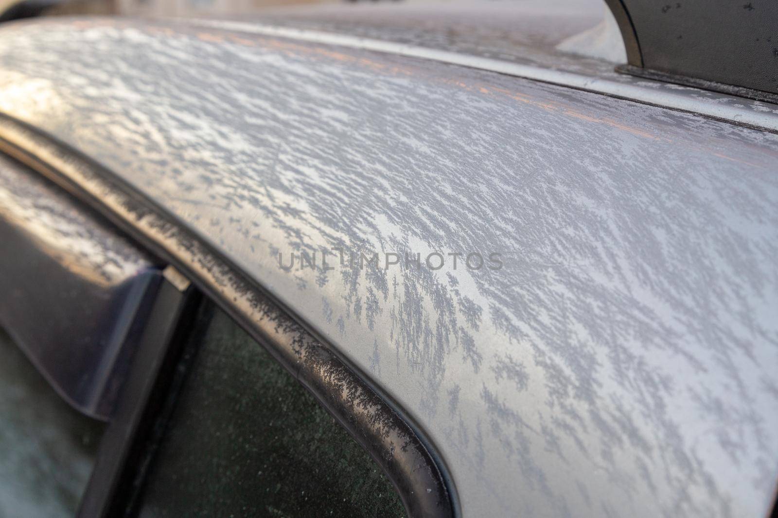 thin ice frost on silver car surface at morning - close-up with selective focus.