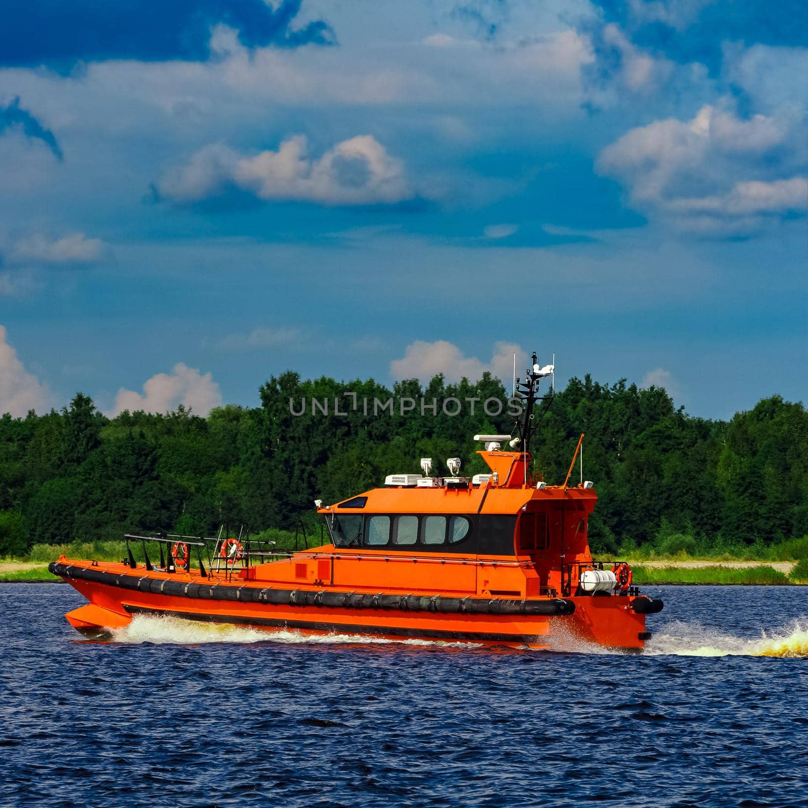 Orange pilot boat moving by the river in Europe. Rescue service