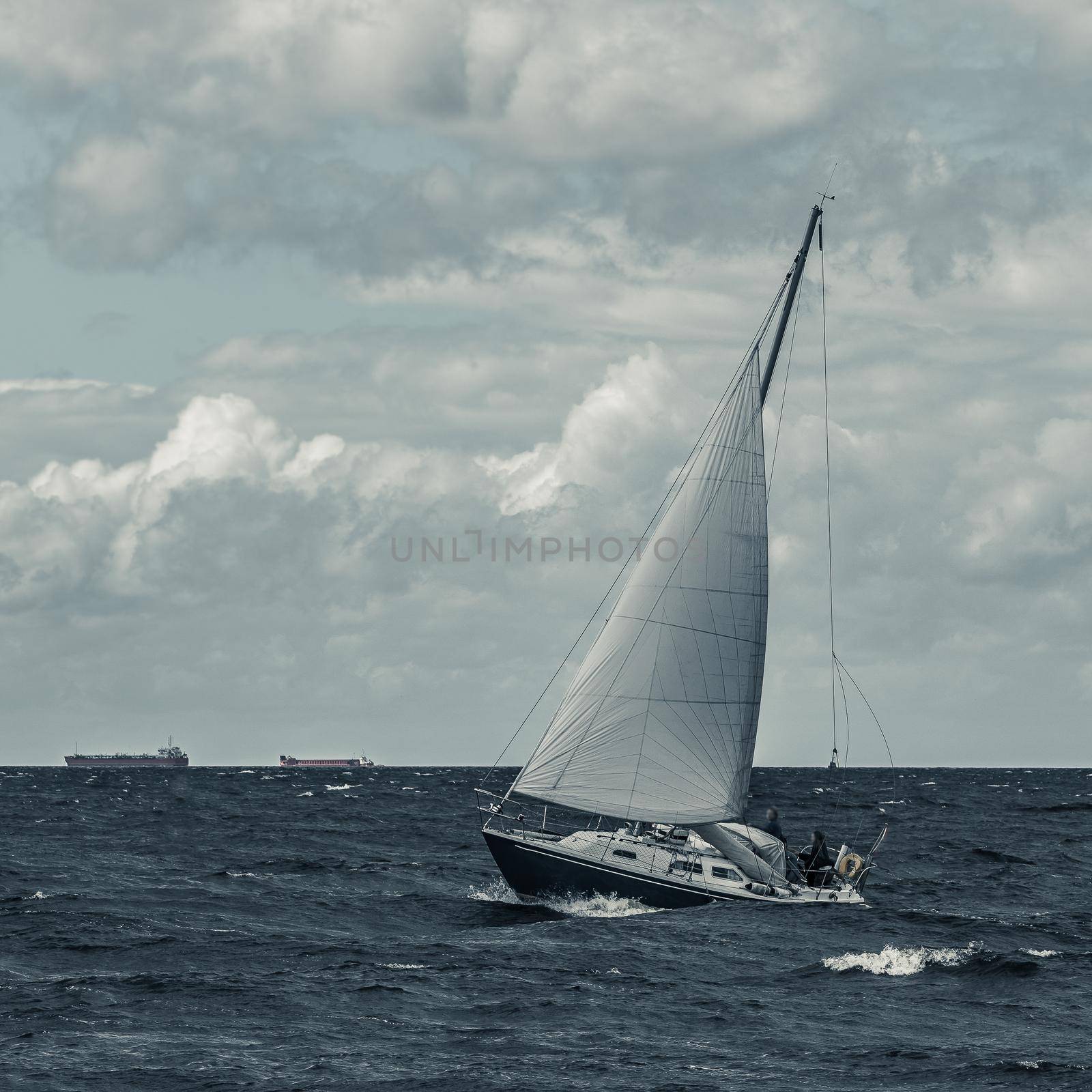 Blue sailboat in a travel at stormy sea. Regata journey. Toned