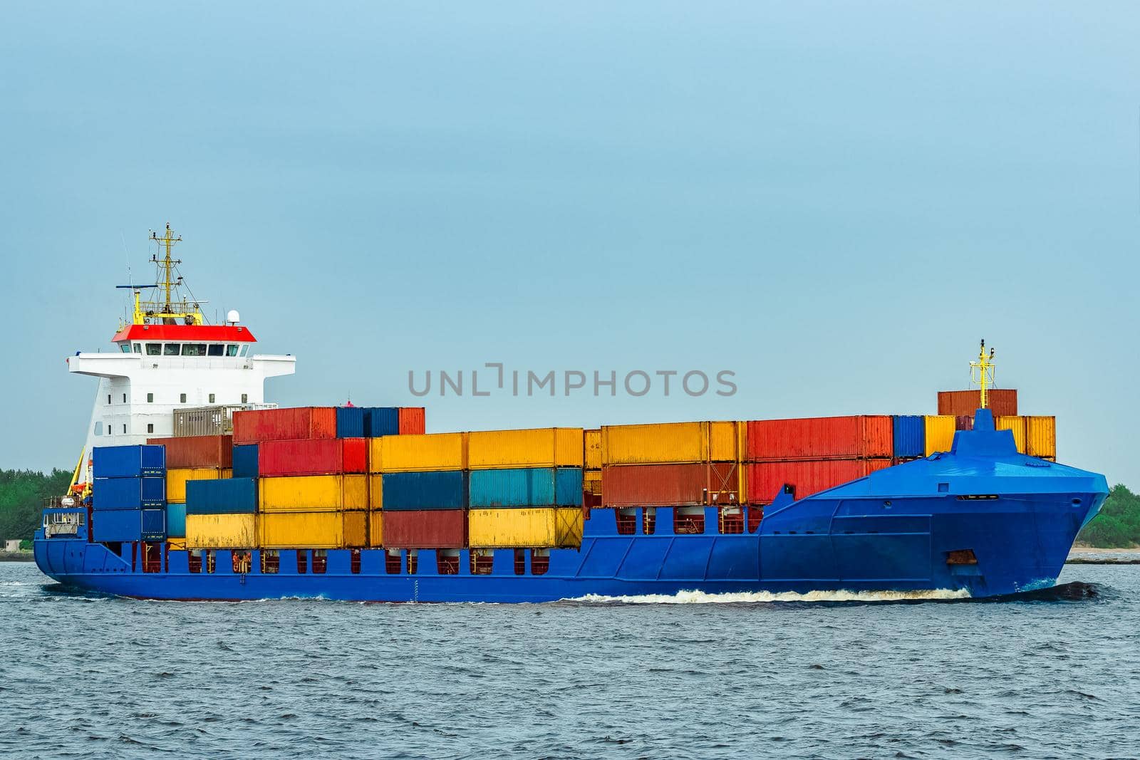 Blue cargo container ship fully loaded underway