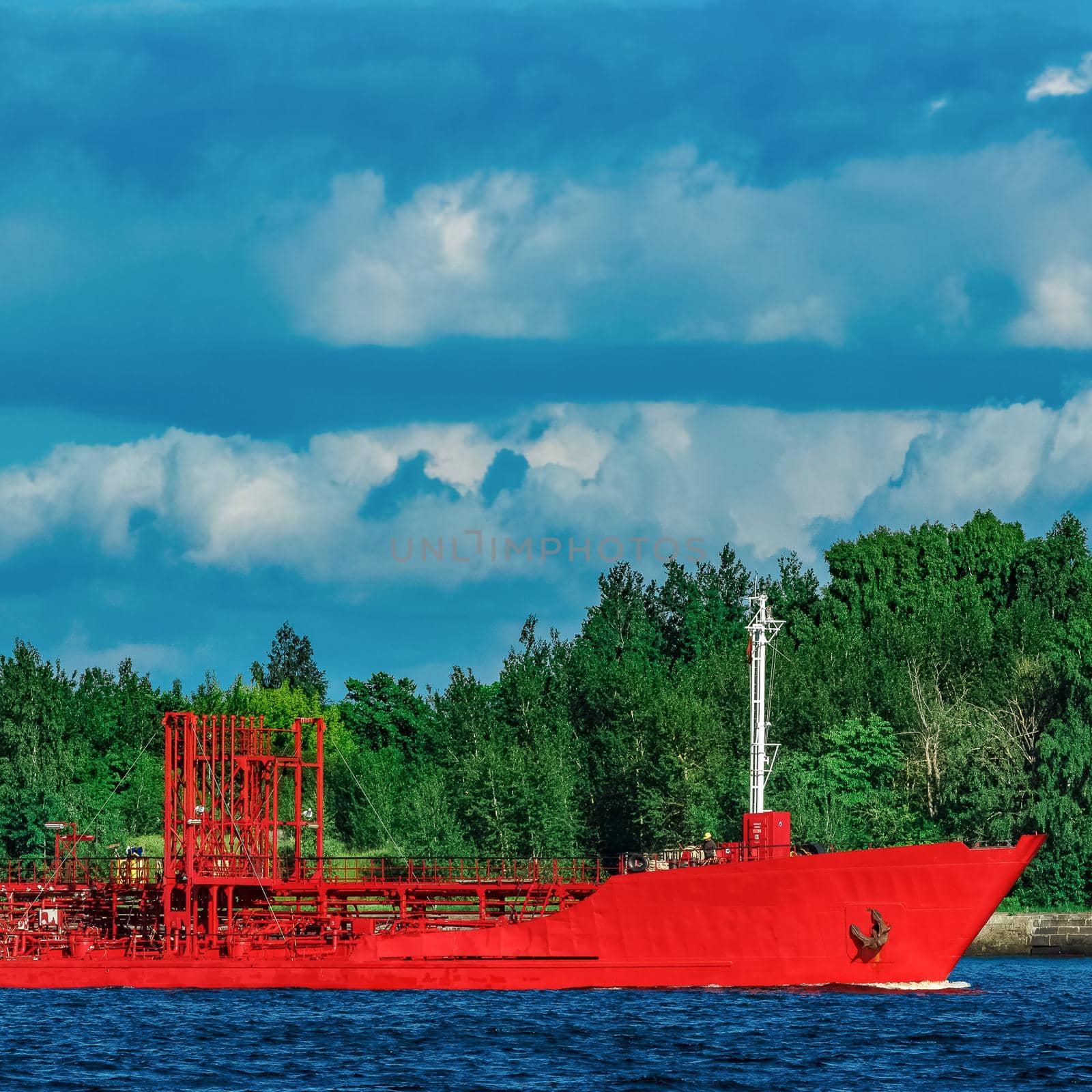 Red cargo tanker ship moving by the river