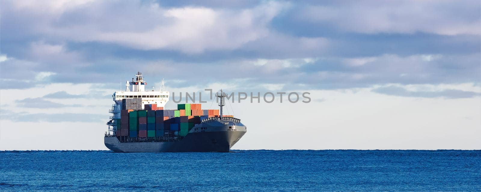 Modern grey container ship moving in still water