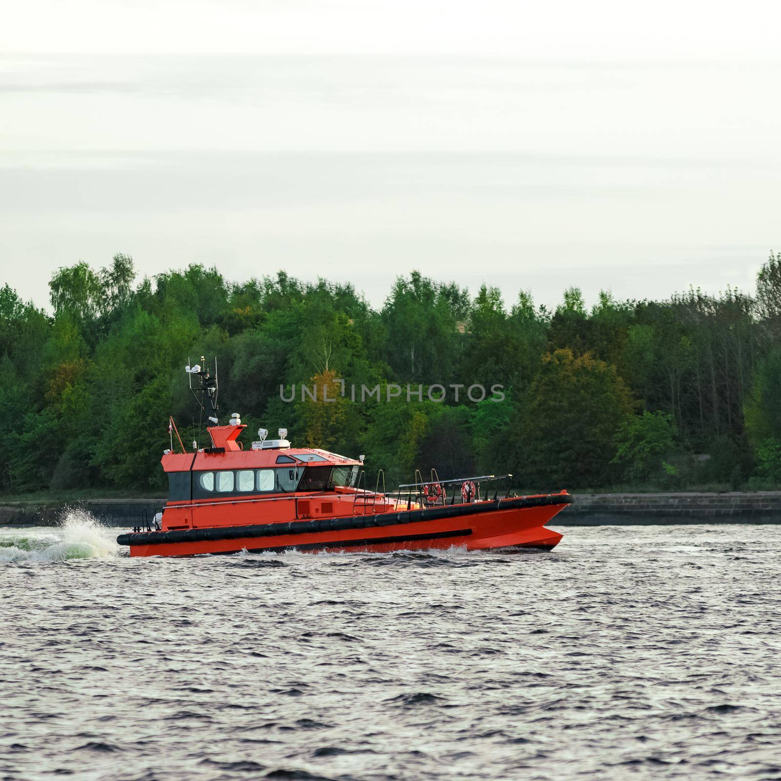 Orange pilot ship sailing on the Daugava river