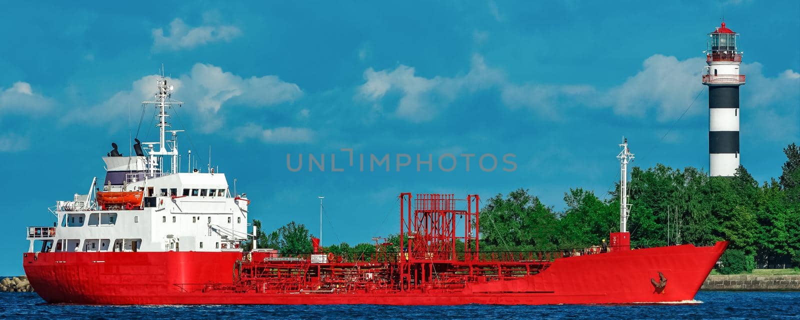 Red cargo tanker ship moving by the river