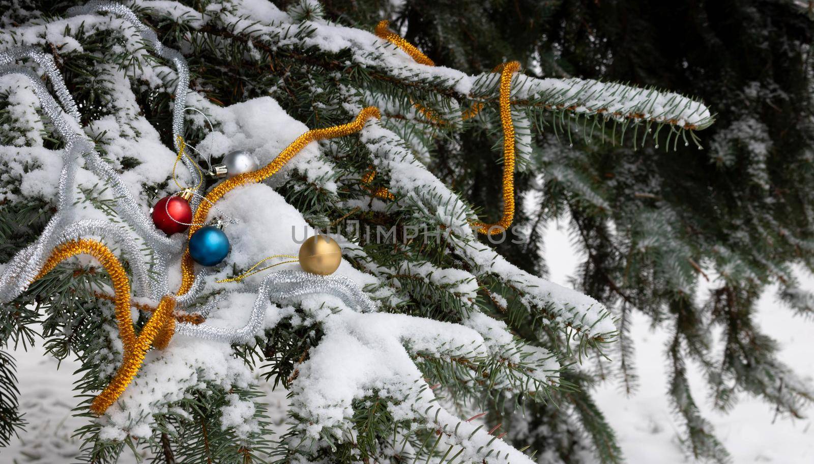 Christmas tree branch in the snow with toys and tinsel . Snow spruce branch in the forest. Russian winter landscape. Space for your text. Christmas composition by lapushka62