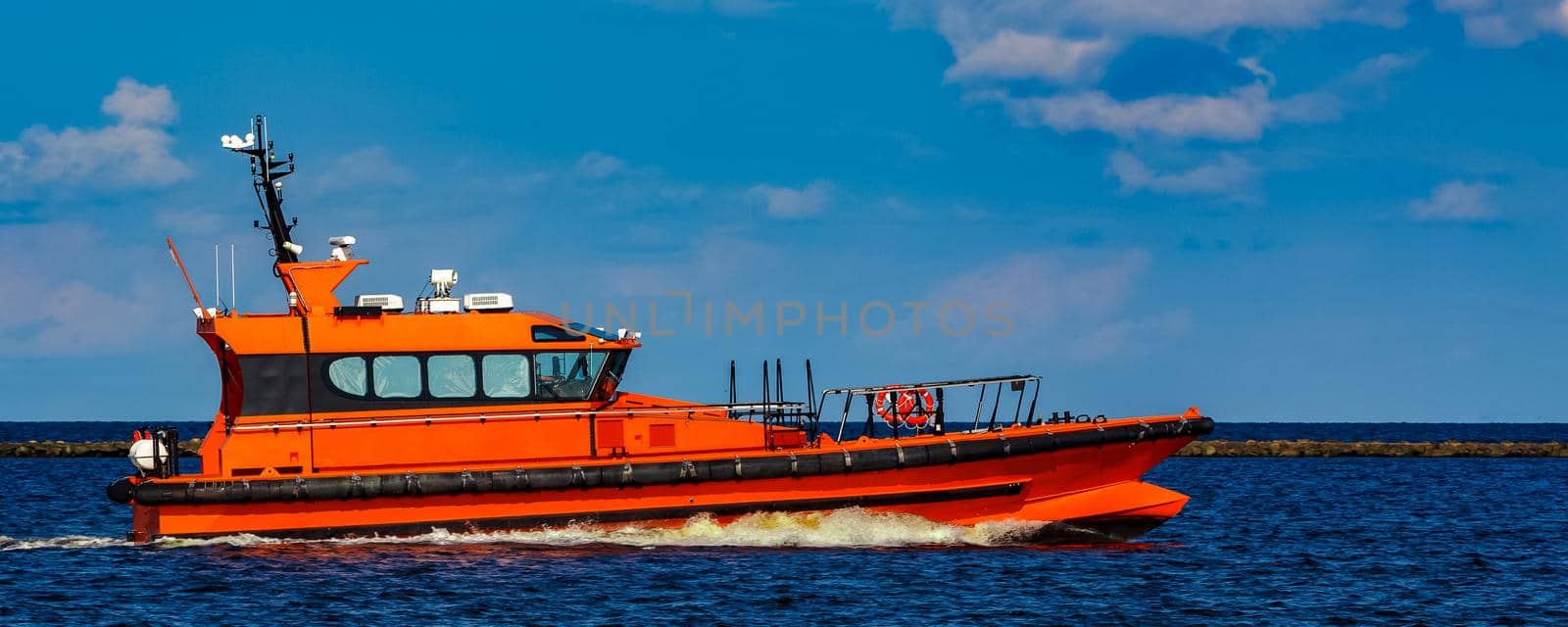 Orange pilot boat moving by the river in Europe. Rescue service