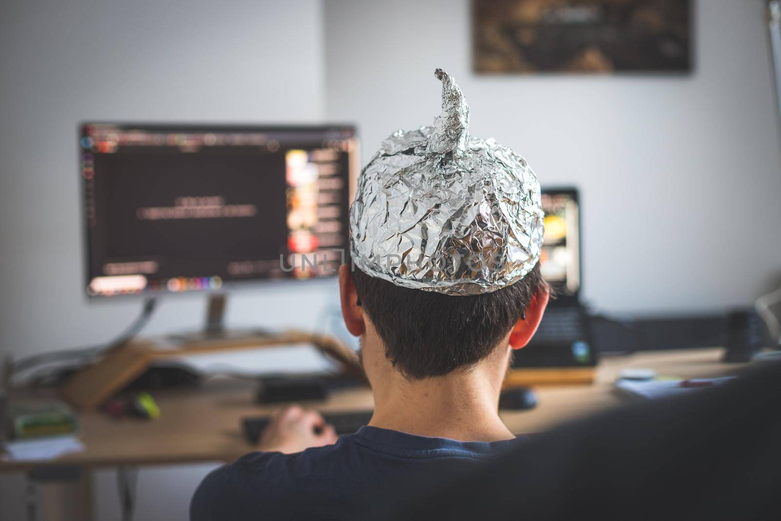 Young man is wearing aluminum cap, conspiracy theory concept