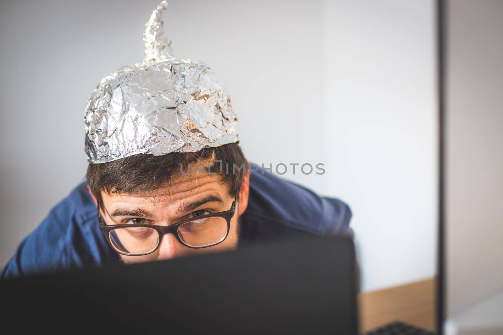 Young man is wearing aluminum cap, conspiracy theory concept