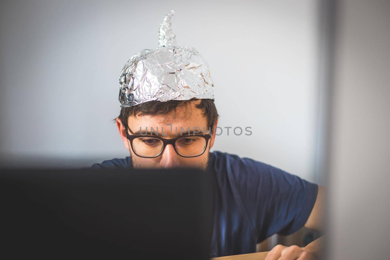 Young man is wearing aluminum cap, conspiracy theory concept