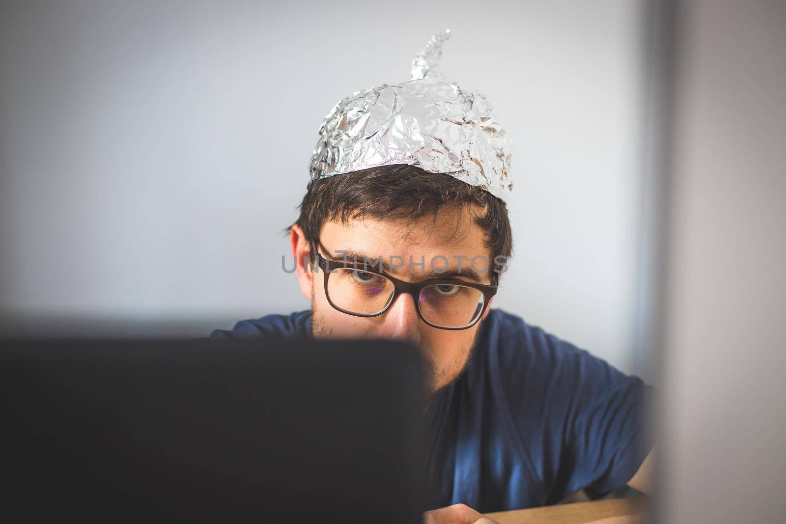 Conspiracy theory concept: young man is wearing aluminum head by Daxenbichler