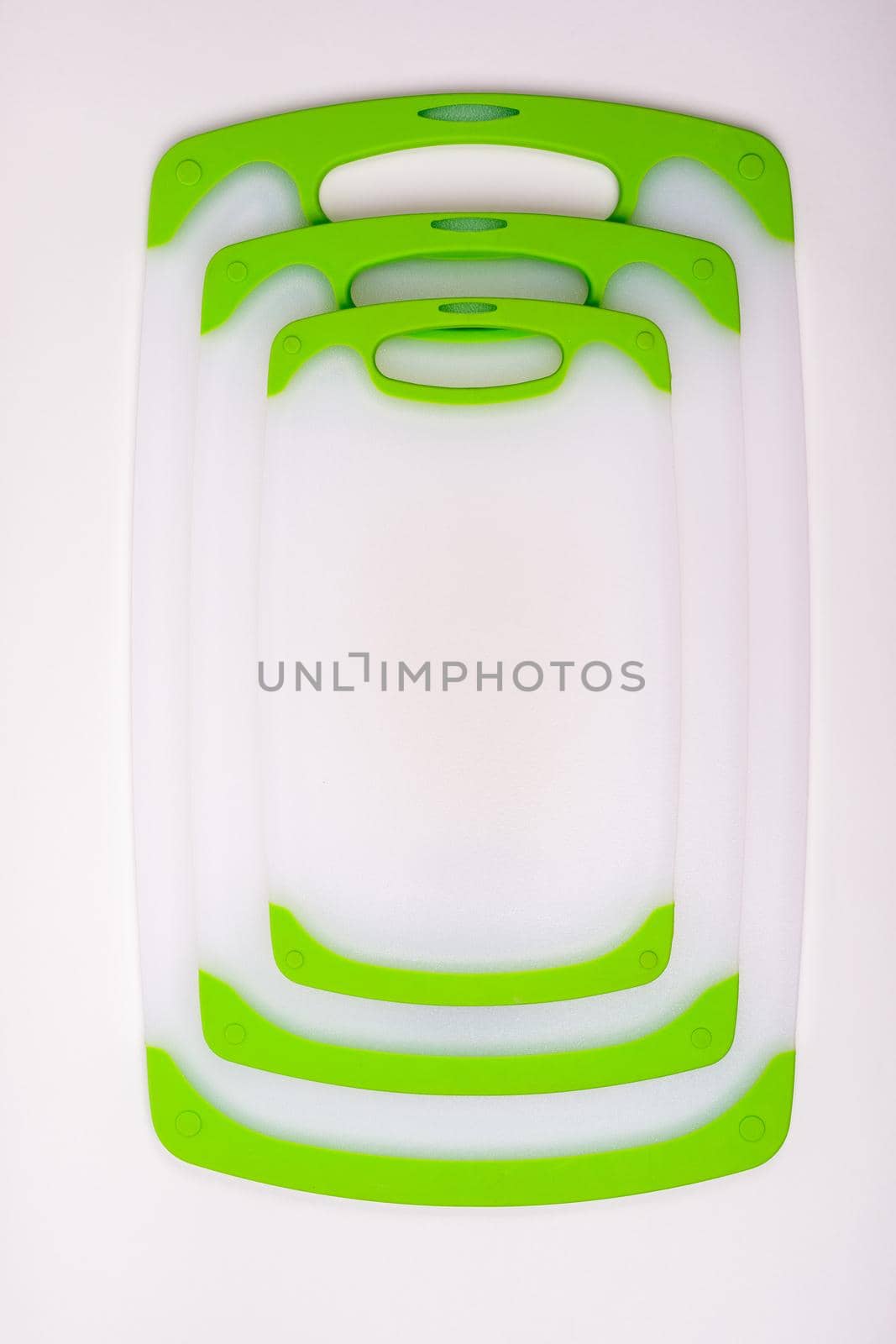 Set of white kitchen cutting boards with green handles for cooking. For cutting food, vegetables, meat, fish. Durable, professional, white plastic.