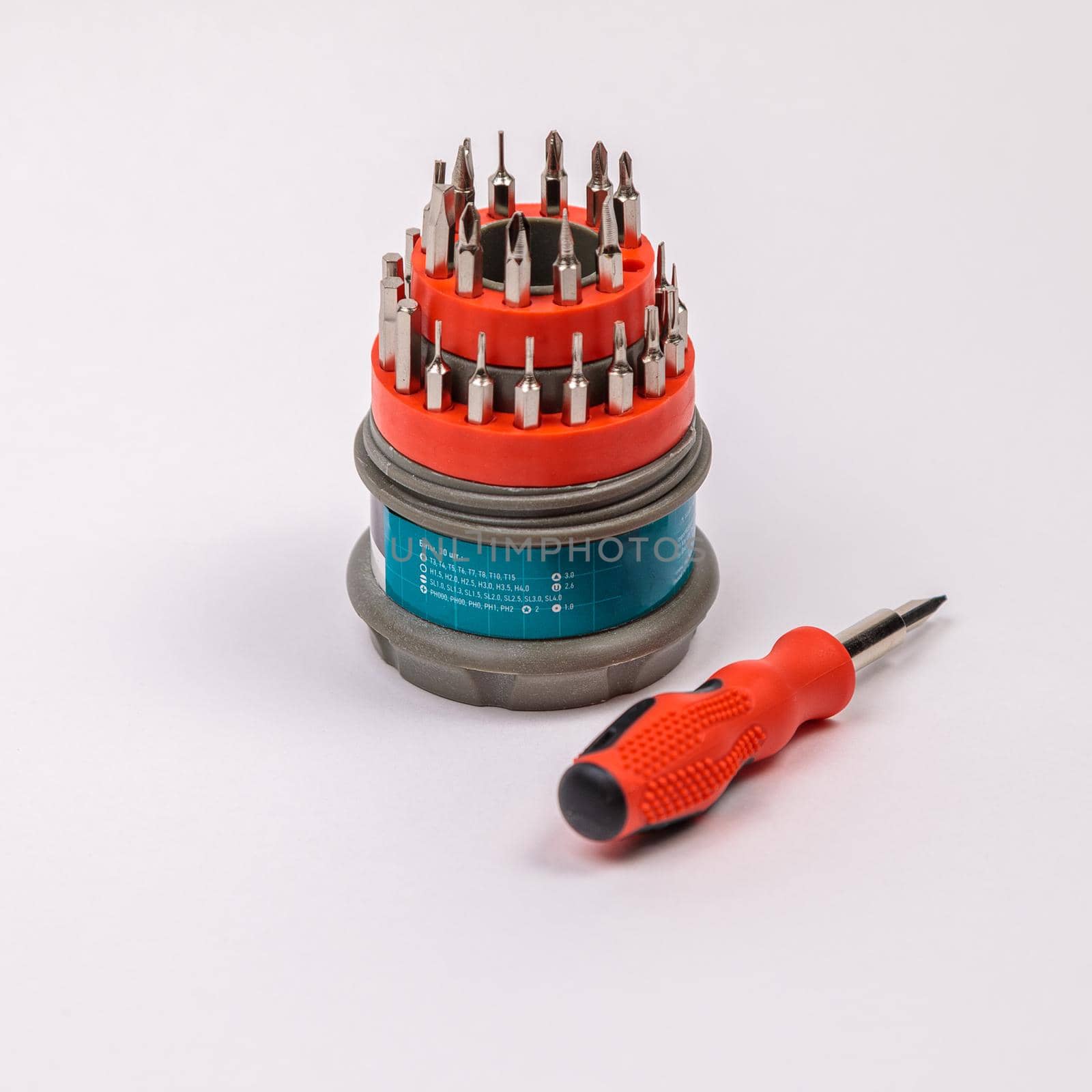 A set of working tools with a screwdriver and bits for repair, in an open plastic box with iron bits, inside a screwdriver.