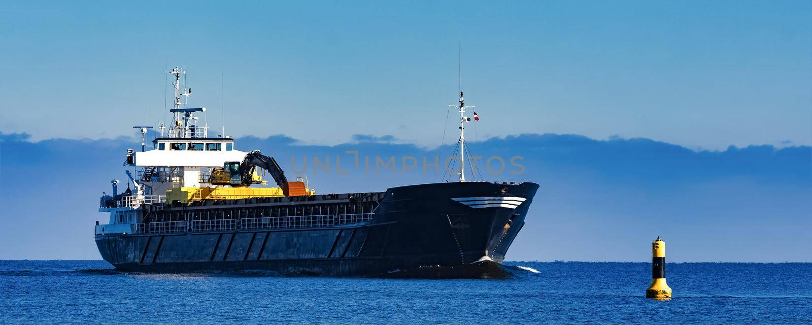 Black Sailing Bulk Carrier. Cargo Ship with Long Reach Excavator Moving in Still Water at Sunny Day by the Sea