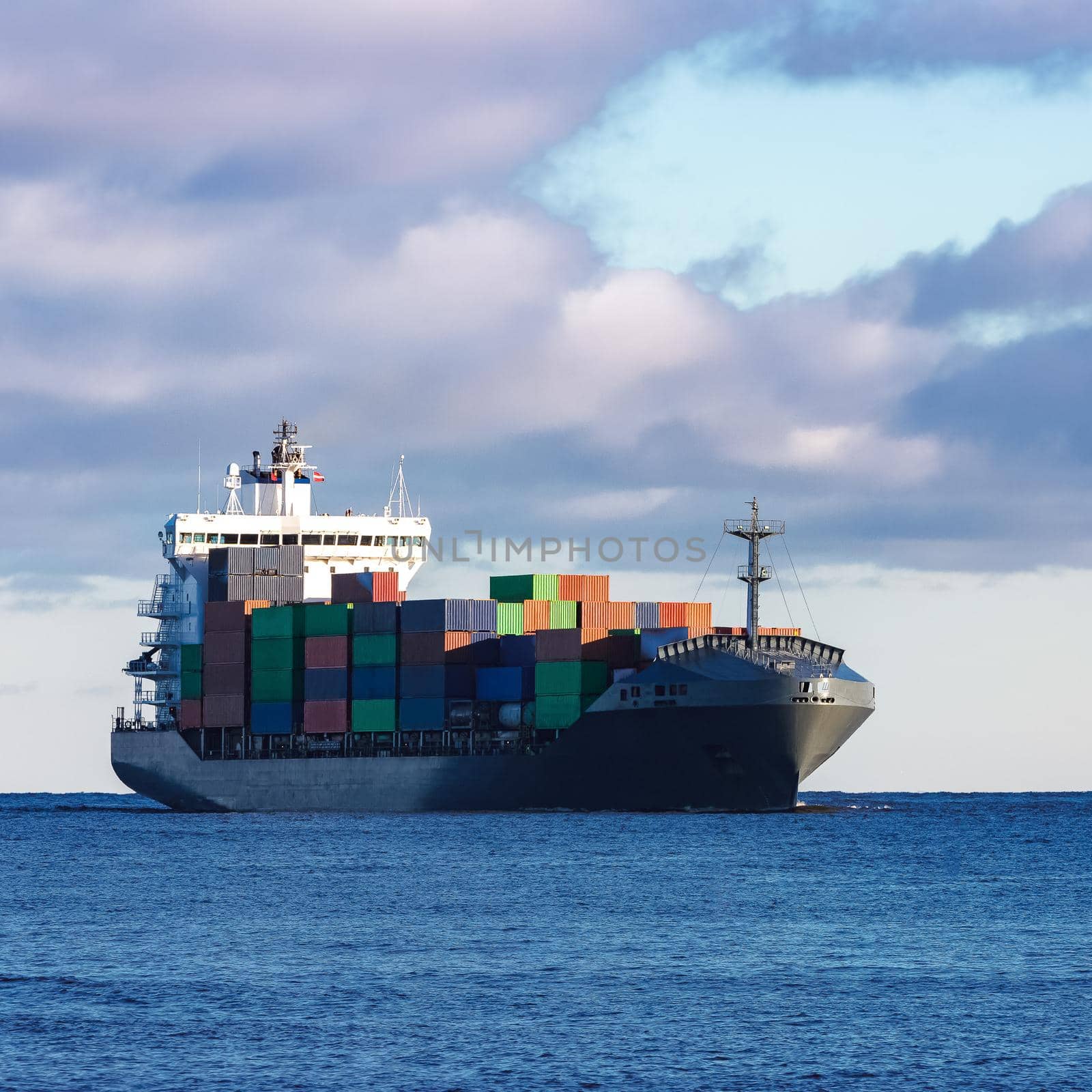 Modern grey container ship moving in still water