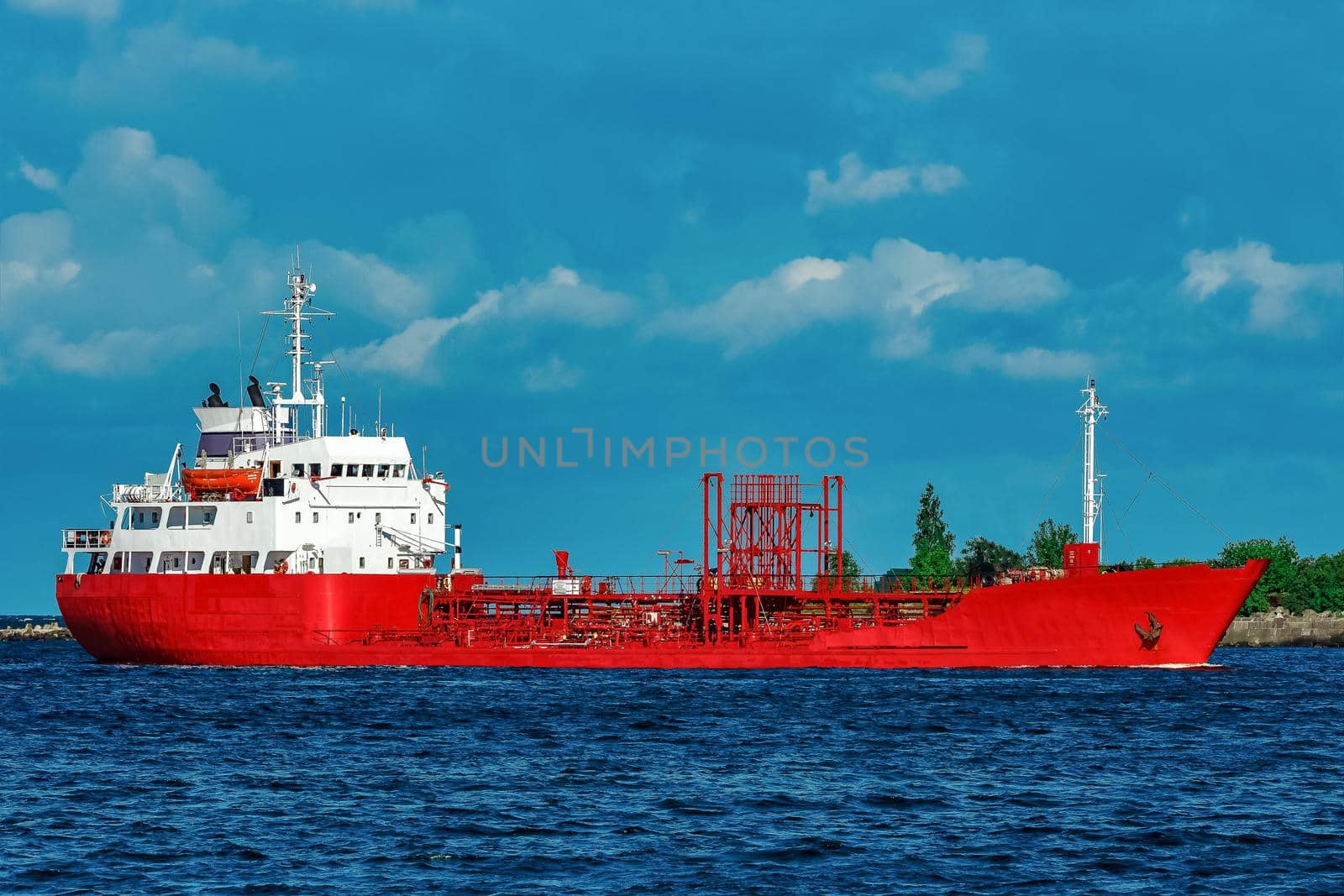 Red cargo tanker ship moving by the river