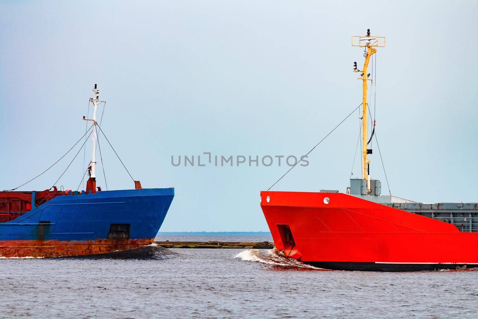 Orange cargo ship sailing past the blue bulk carrier