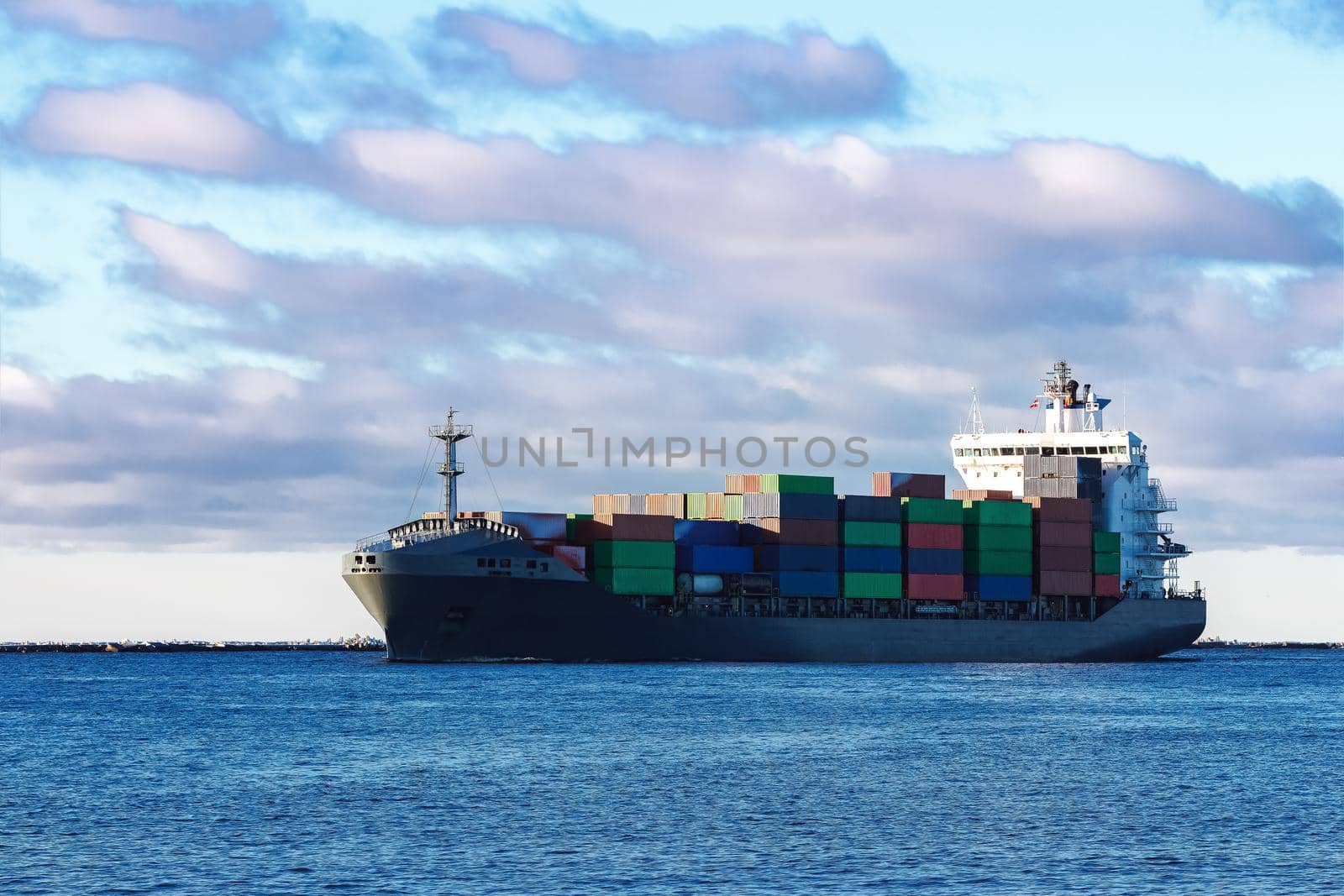 Modern grey container ship moving in still water
