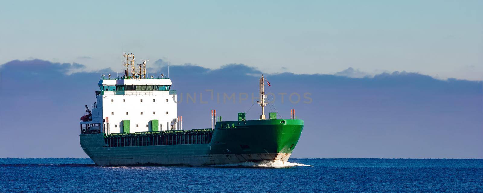 Green cargo ship moving in still water of Baltic sea