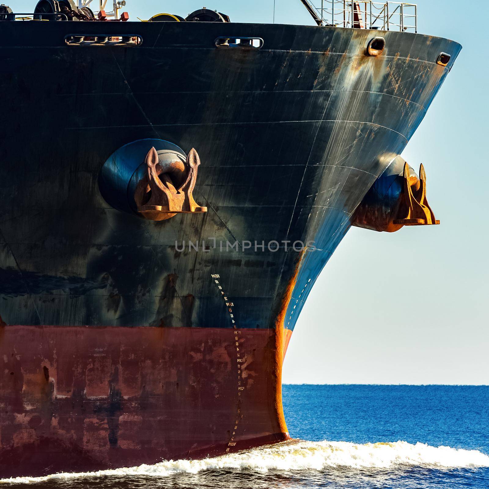 Black cargo ship's bow in still water. Riga, Europe