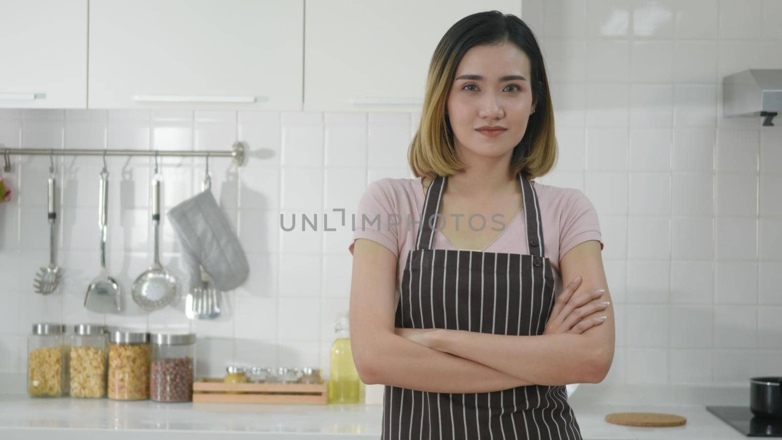 Portrait Asian young happy beautiful woman smiling standing crossing hands on kitchen she looking to camera. female housewife holding arms crossed confident luxury enjoy posing cooking. slow motion