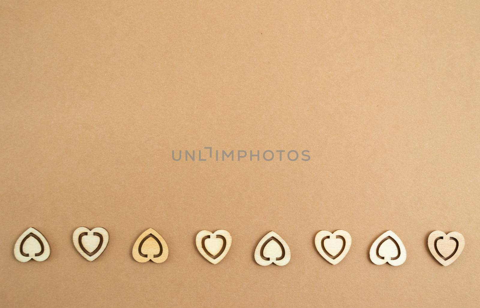 Wooden hearts on a pastel craft paper background. Abstract background with wood cut shapes. Sainte Valentine, mother's day, birthday greeting cards, invitations. Copy space.