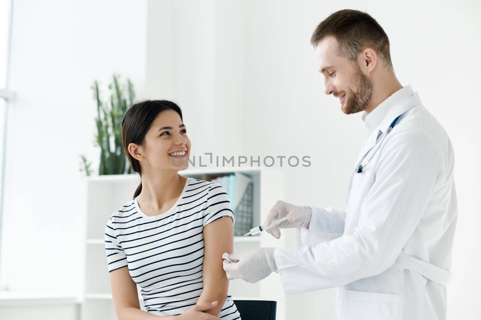 male doctor in a white coat injecting a woman's hand in a health hospital vaccination by SHOTPRIME