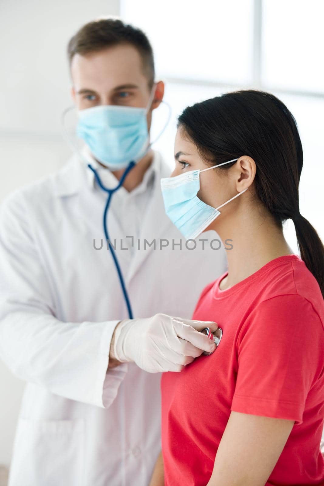 doctor with a stethoscope examines a patient wearing a medical mask breathing lungs . High quality photo