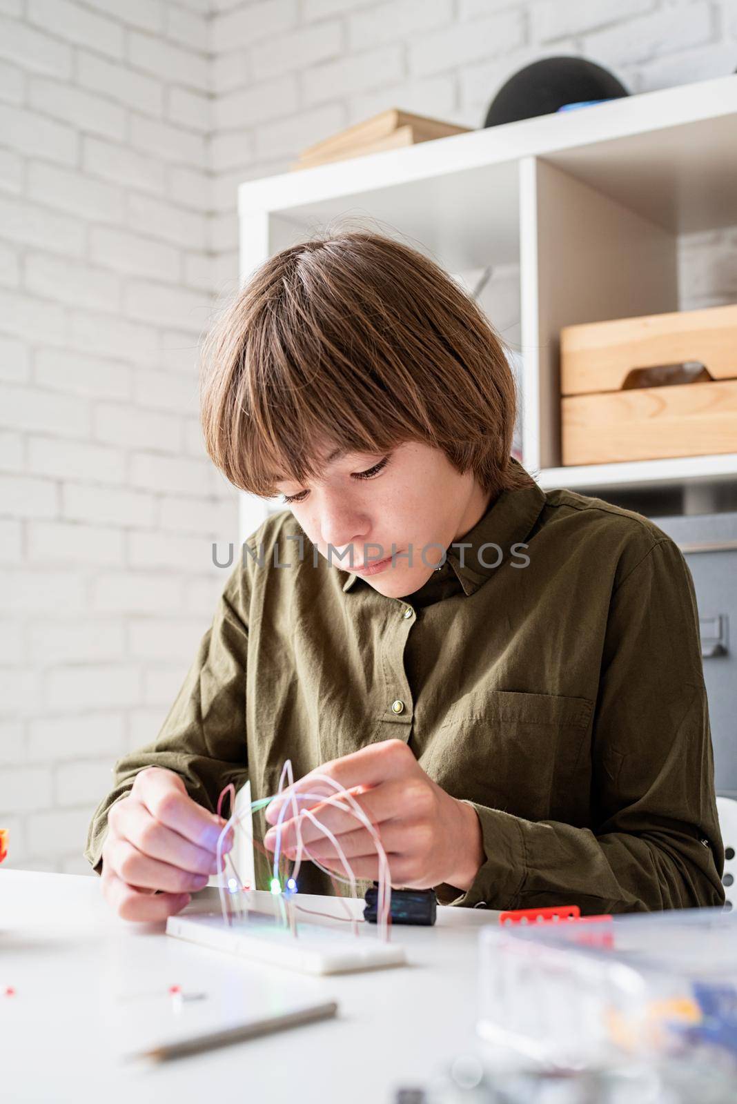 12 year old boy constructing a robot car sitting at the table playing with lights