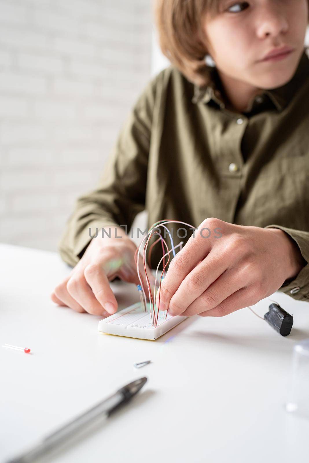 boy working with LED lights on experimental board for science project by Desperada