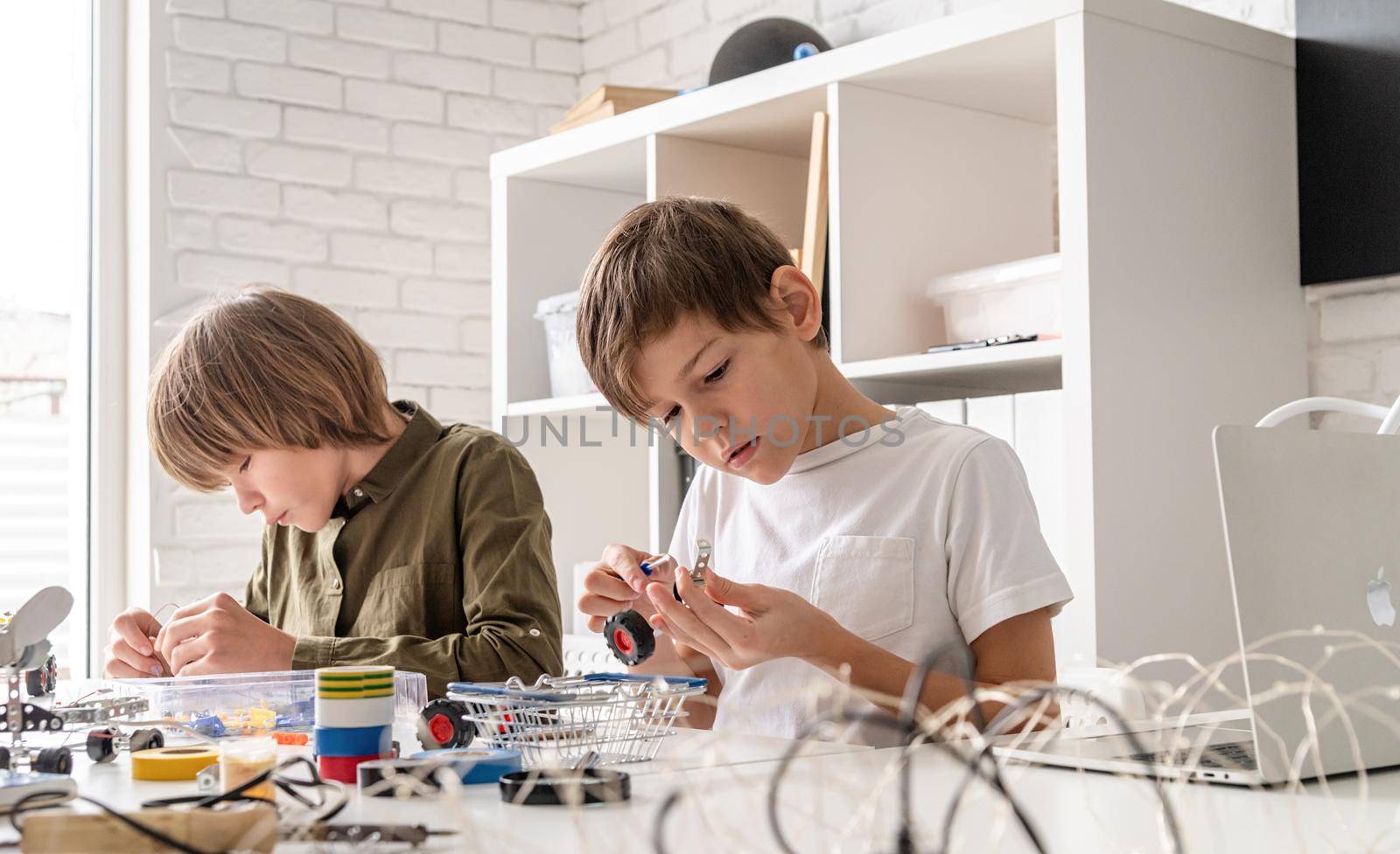 Young boys having fun constructing robot cars at the workshop by Desperada