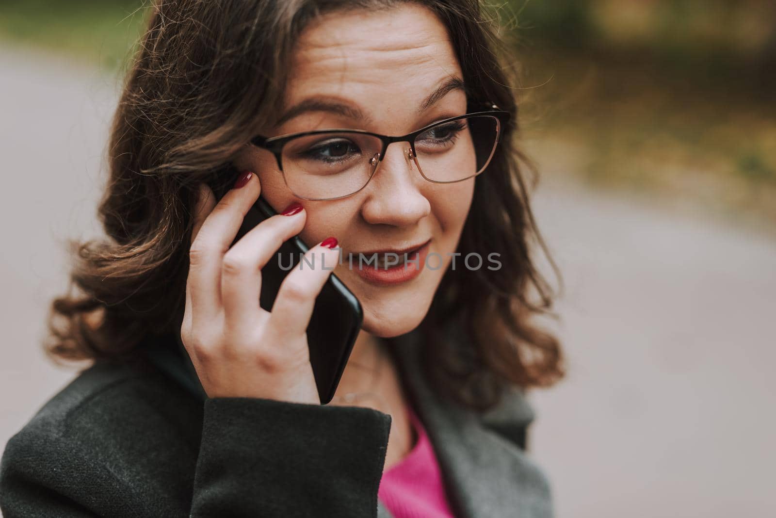 Pretty lady having pleasant phone talk outdoors by monakoartstudio