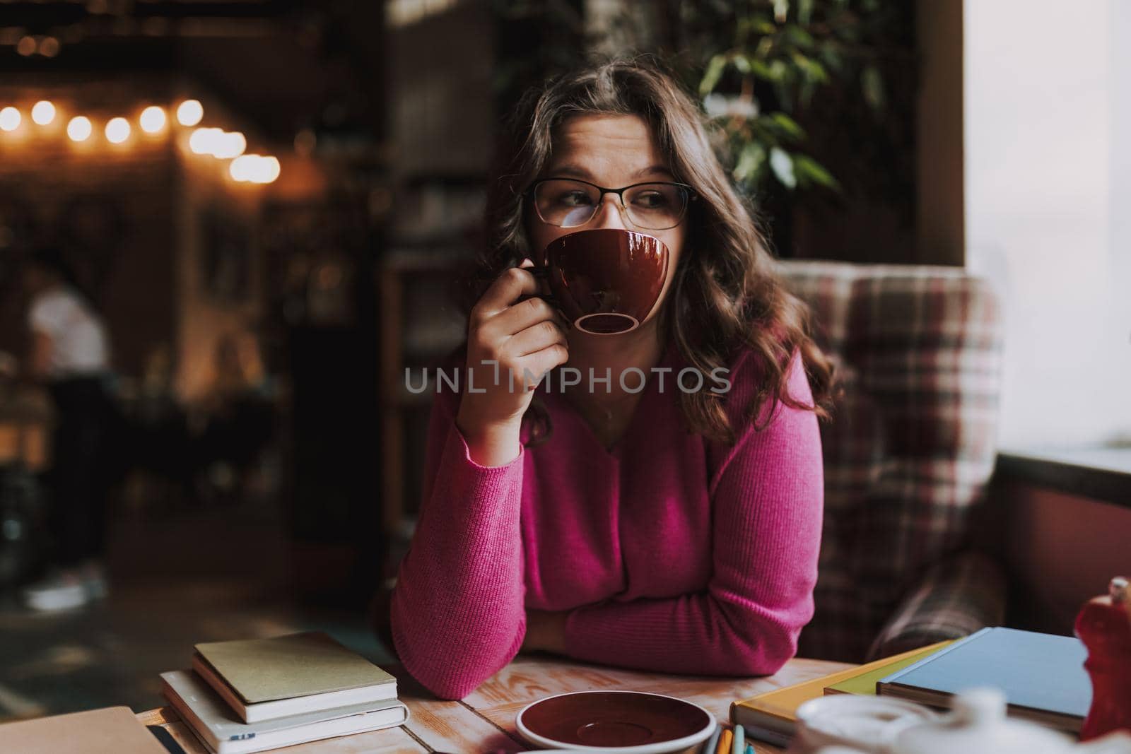 Beautiful lady wearing glasses and enjoying tea while having lunch and holding cup