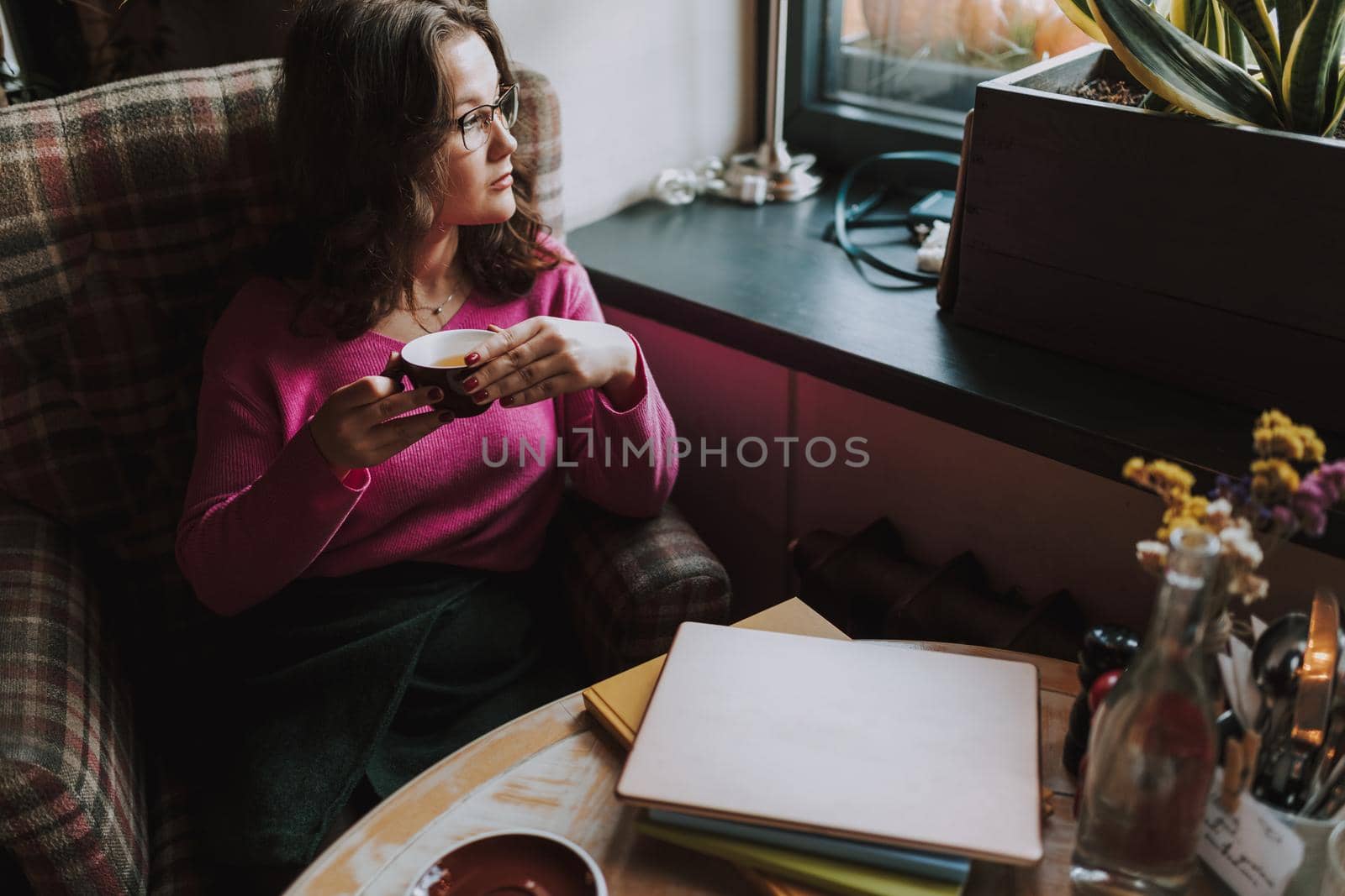 Young woman looking away and enjoying hot drink by monakoartstudio