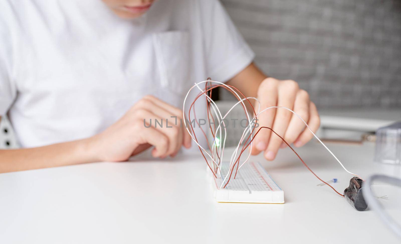 boy working with LED lights on experimental board for science project by Desperada