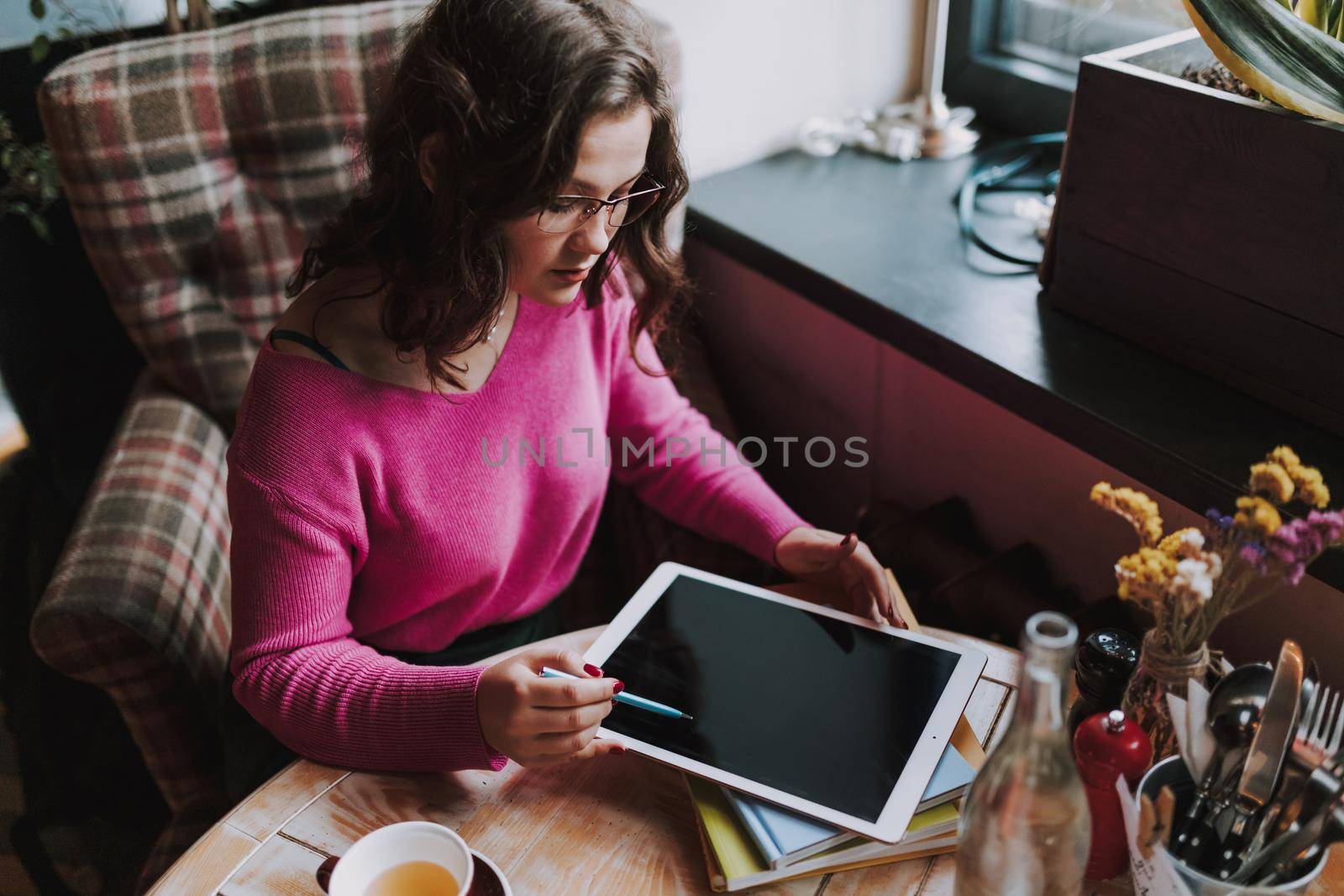 Top view of attractive lady looking at digital tablet screen while sitting in cafe