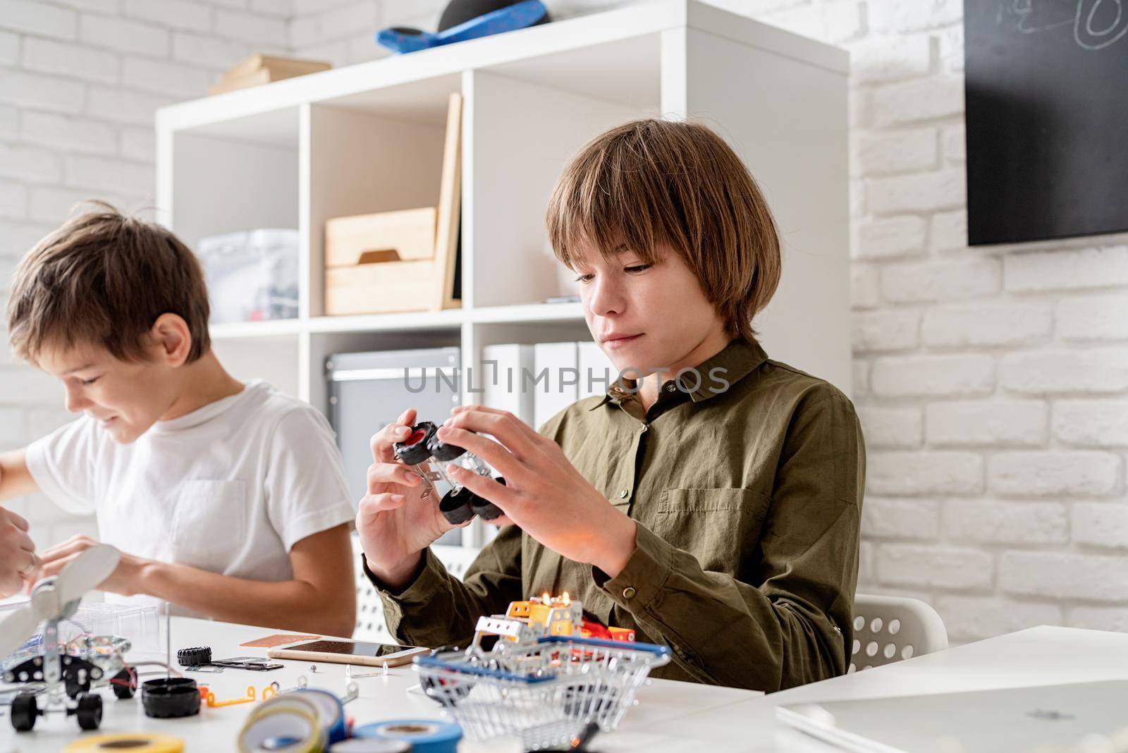 Young boys having fun constructing robot cars at the workshop by Desperada