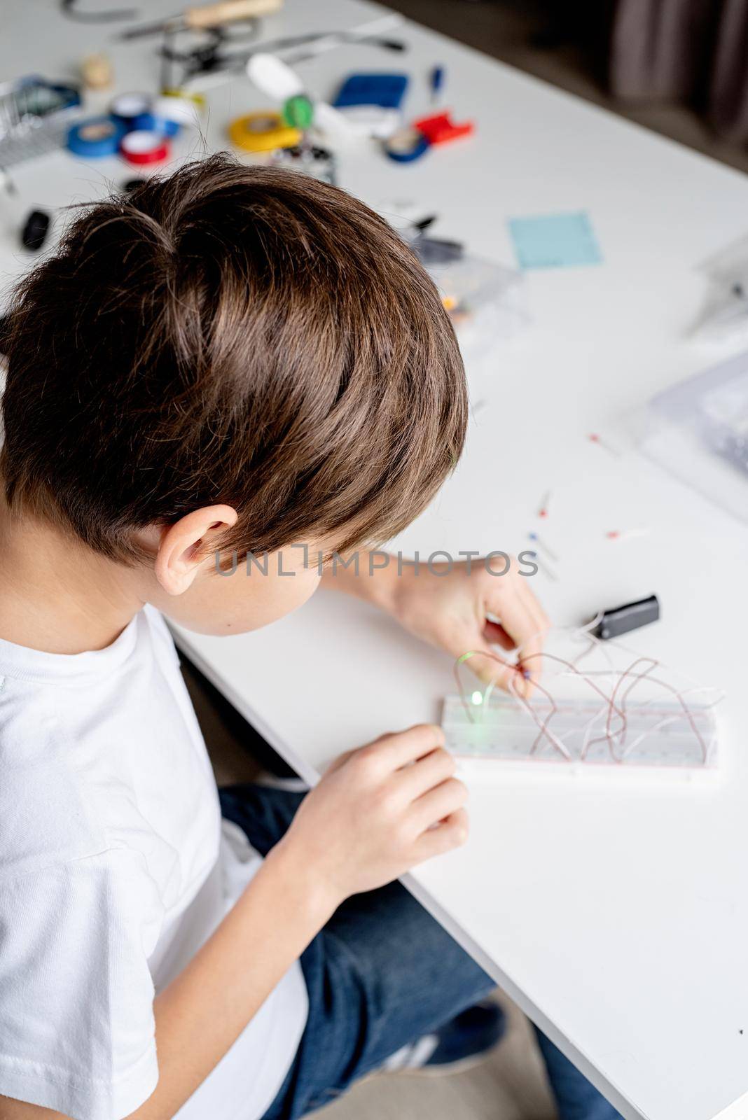 boy working with LED lights on experimental board for science project by Desperada