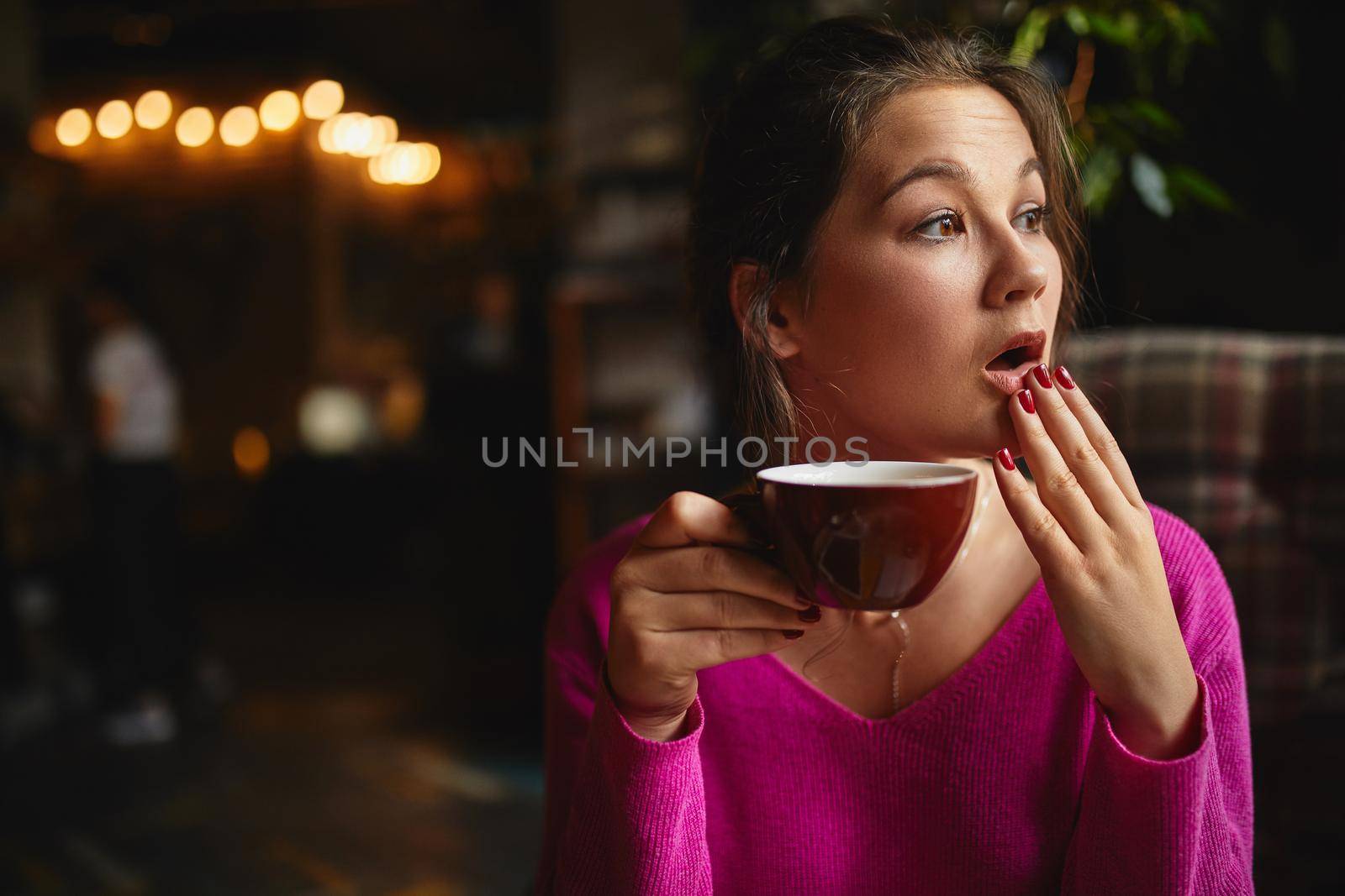 Waist up of pretty young brunette having break with coffee while holding red cup