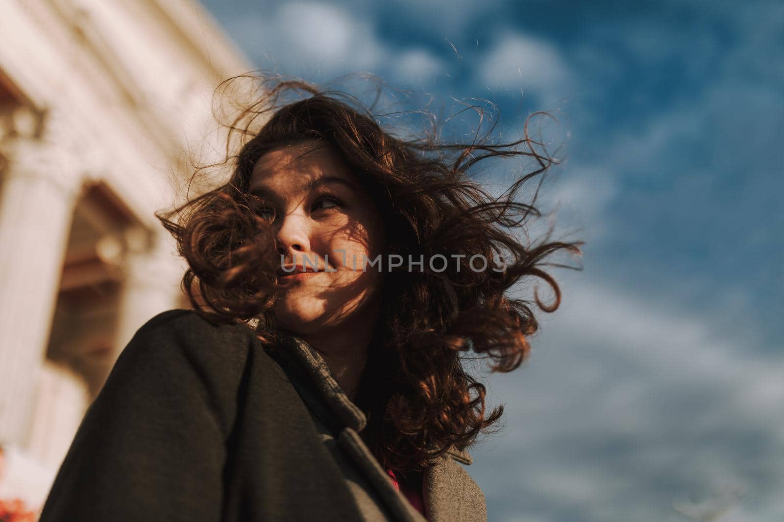 Low angle view of beautiful woman standing on the street while posing against the blue sky