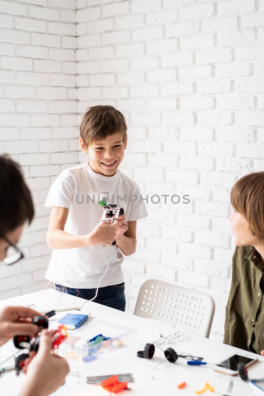 Young boys having fun constructing robot cars at the workshop by Desperada