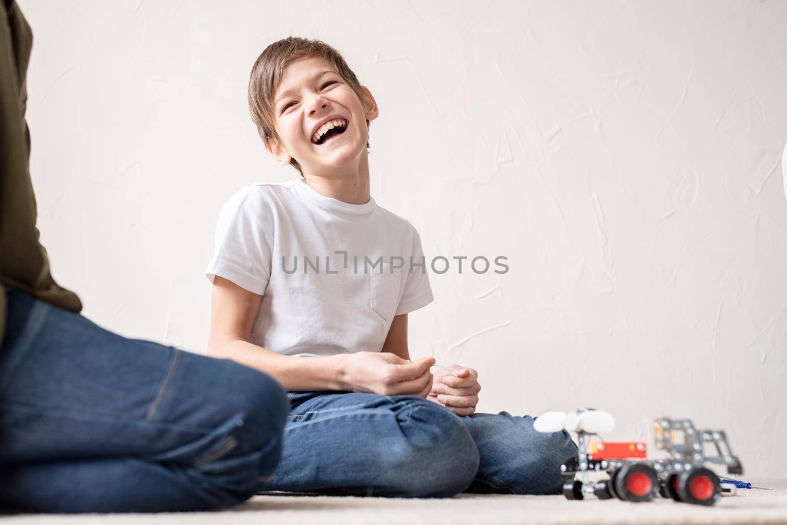 Young boys having fun constructing robot cars at the workshop by Desperada