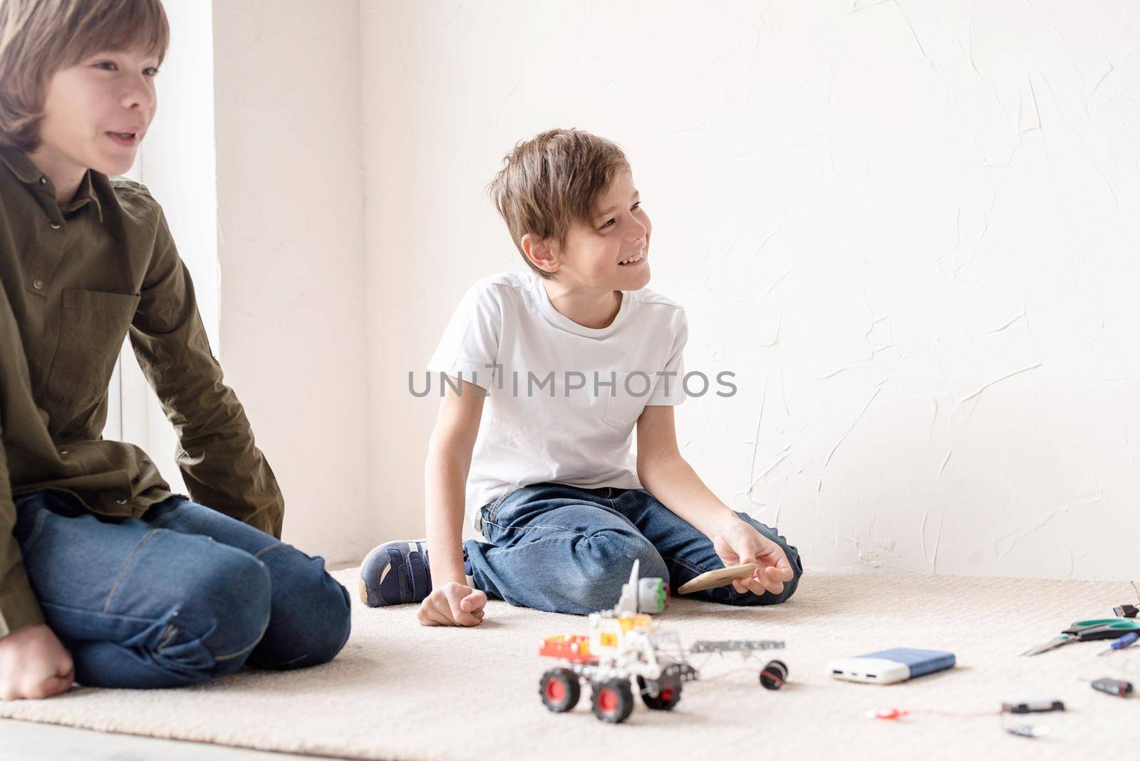 Young boys and teacher having fun constructing robot cars at the workshop, top view by Desperada