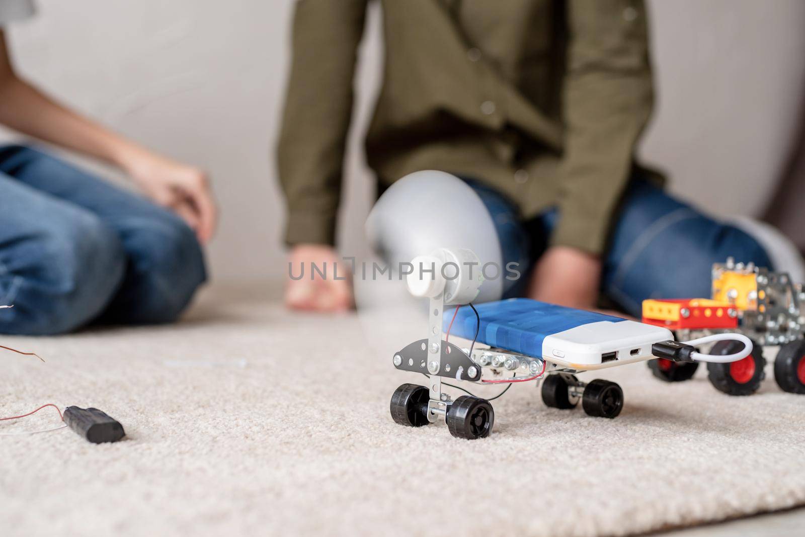 Young boys having fun constructing robot cars at the workshop by Desperada