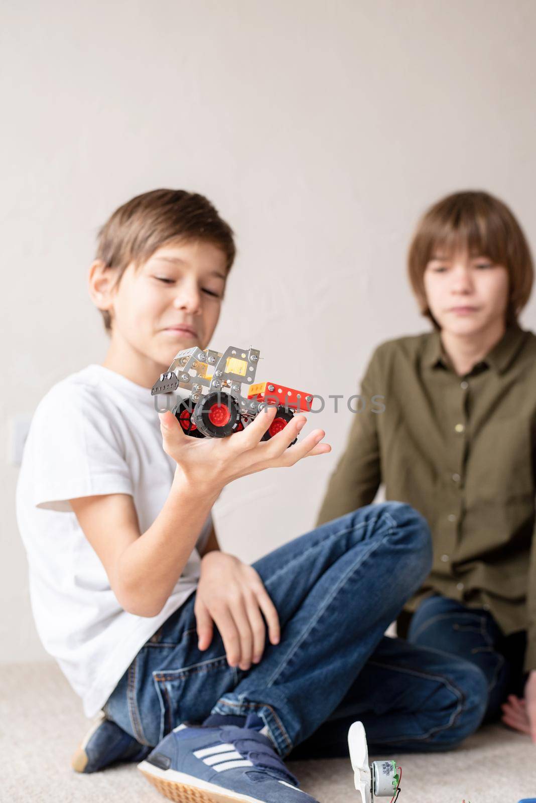 Young boys having fun constructing robot cars at the workshop by Desperada