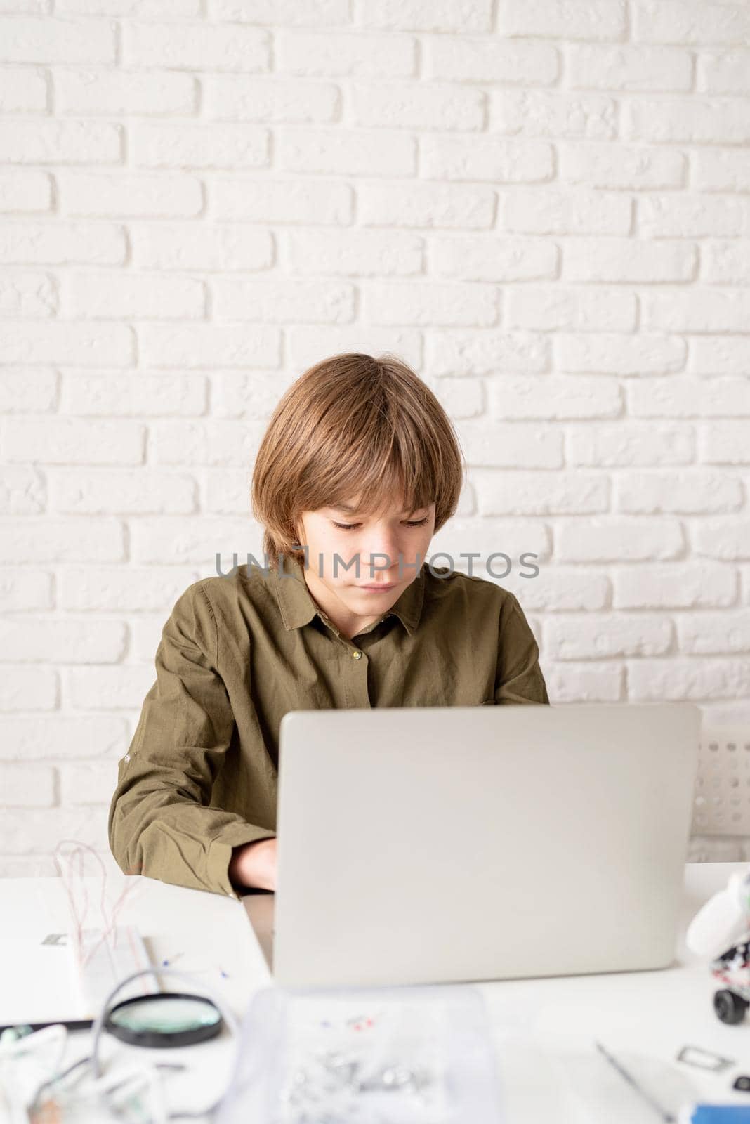 Young boy working or studying on the laptop at home by Desperada