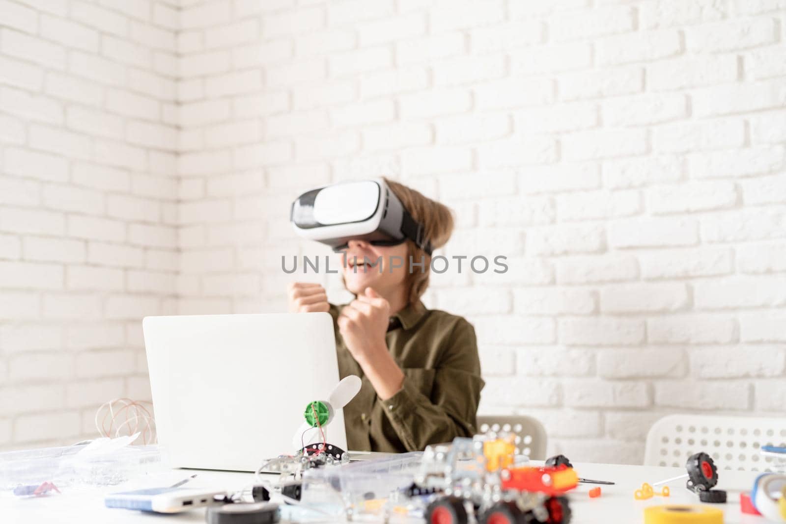 Smiling teen boy in virtual reality glasses playing the game, selective focus by Desperada