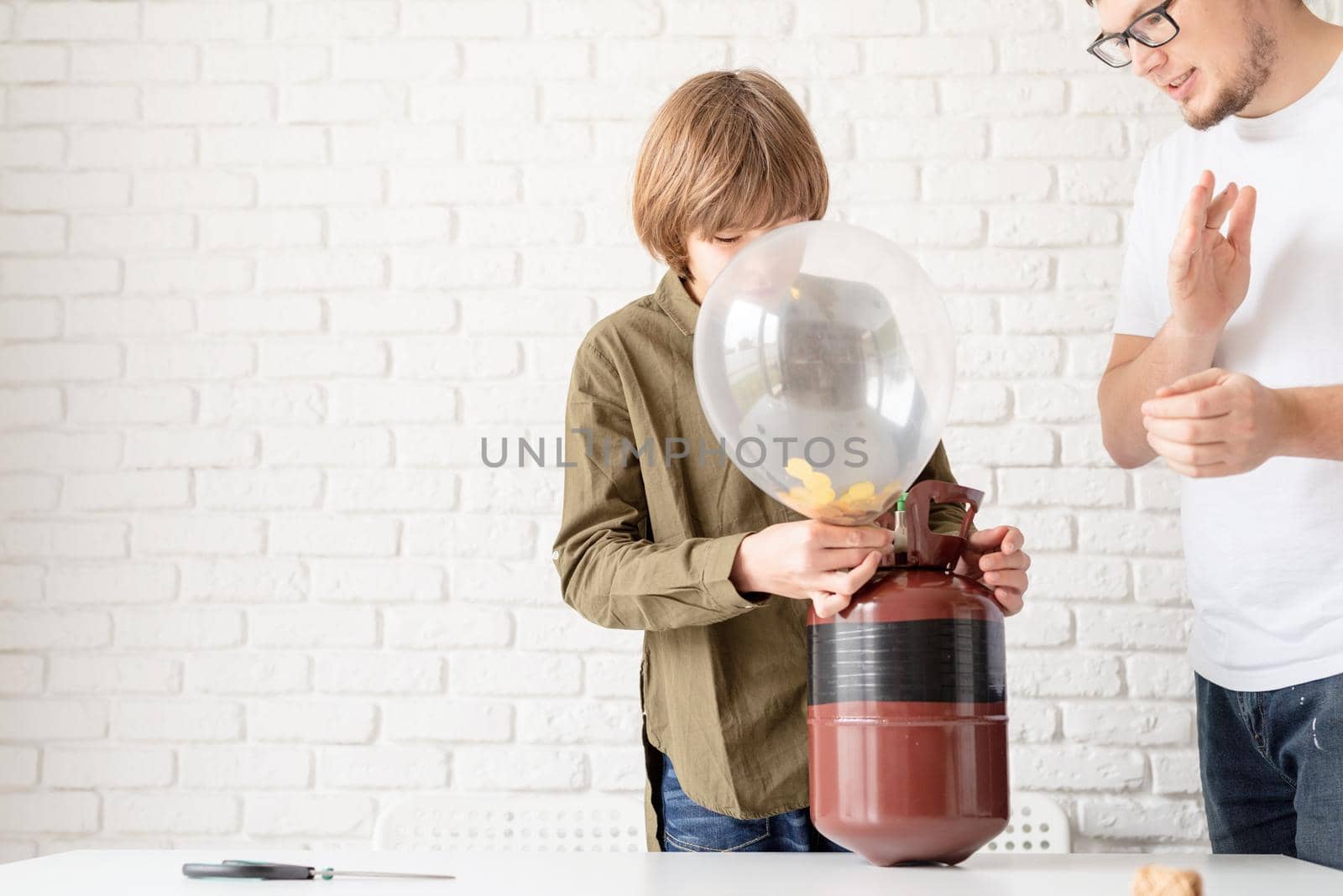 Funny boy blowing up a balloon with helium